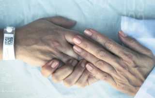 Closeup of a doctor clasping a patient's hands in theirs